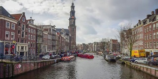 阿姆斯特丹运河，北荷兰，荷兰王国。国家博物馆的塔景。街道和阿姆斯特丹运河，自行车和自行车，游艇，生活船。