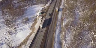 汽车和货车在冬季高速公路上行驶，无人机在上面飞行。鸟瞰图车辆在雪道上的冬季景观