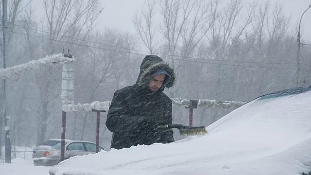 Man cleaning snow from car