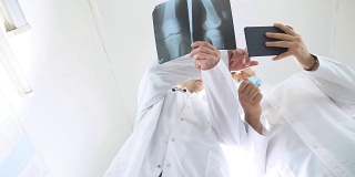 男医生一边使用平板电脑一边互相咨询病人的x光片。医院的医务人员检查x光照片。两位白种人医生观看核磁共振图像并讨论它。低角度视图特写