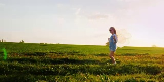 戴着粉色眼镜和气球的小女孩。走在乡间小路上，背景是绿色的草地和蓝色的天空。一个快乐的童年，一个童年的梦想