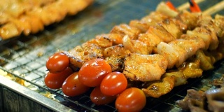 鸡肉串在一根棍子上。用鸡肉和番茄做成的烤肉串。夜市，芭堤雅，宗田。泰国菜。市场上有亚洲异国菜肴