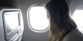 近距离观察:年轻女子透过飞机的窗户，关上百叶窗。