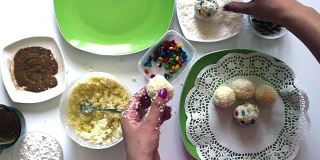 一位妇女正在用炼乳、椰子屑和杏仁准备糖果。用彩釉装饰糖果。