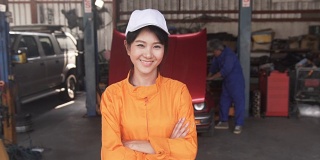 多莉特写正面视图:亚洲年轻女性汽车技工是微笑