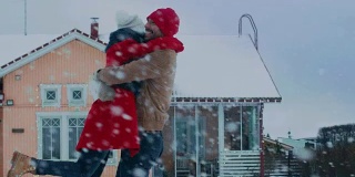 美丽的年轻夫妇跳舞和旋转-拥抱在他们田园别墅的后院，而雪花浪漫地落下。快乐的年轻人在神奇的冬天时间。