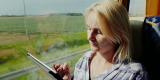 一名年轻女子乘公共汽车旅行，享受着平板电脑。窗外是一片风景如画的地区，公交车很快就到了