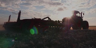 稳定器镜头:拖拉机在日落时耙地
