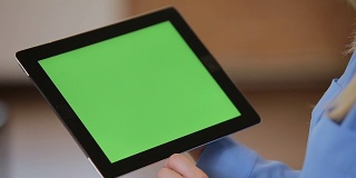 年轻迷人的女人使用黑色平板与绿色屏幕在现代办公室的特写。色度键。