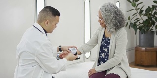 医生在老年女性病人身上放置血压仪