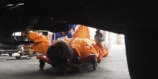 小车低角度视角亚洲年轻女性汽车技工在汽车发动机下工作