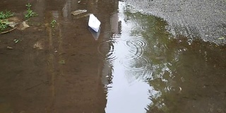 Paper boat floating in a puddle