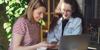 两个女学生使用智能手机的特写。迷人的金发女孩指着触摸屏和她的朋友聊天。现代科技对于年轻人的概念。
