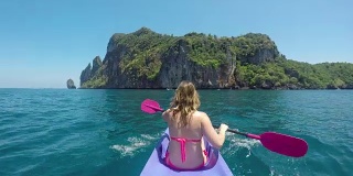特写:在泰国偏远的岛屿上，一名白种妇女划船向悬崖。