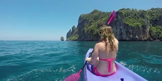 近距离观察:在热带海景平静的海洋中，一名难以辨认的女子划着皮艇。
