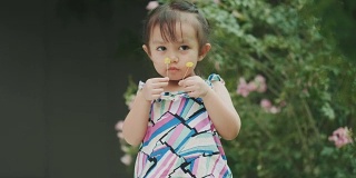 泰国可爱的小女孩抱着花，在花园里闻着花香