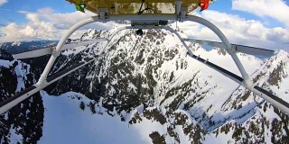 在美国西北部太平洋地区的雪山之间高速飞行的直升机下的POV山激烈的动作快速转弯特写