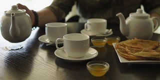 一个男人的手的特写，他正在桌子上吃早餐，倒茶