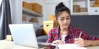 年轻的亚洲女性在家工作，年轻的女性业主开始在线业务，中小企业，交付项目，女性在线业务或中小企业概念。