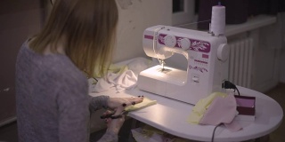 女时装设计师/裁缝/裁缝晚上在家里用缝纫机工作。红发女职工