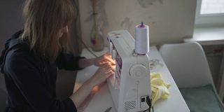 女时装设计师/裁缝/裁缝晚上在家里用缝纫机工作。红发女职工