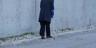 老年残疾人背景。这位老人拄着拐杖走在公共场合。