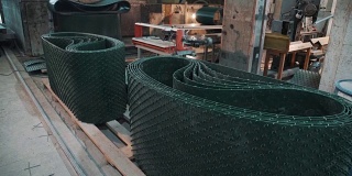 工厂里一堆堆带刷毛的绿色塑料布，还有工作台