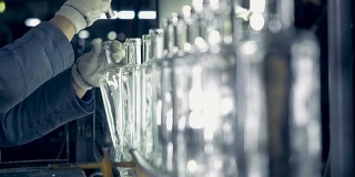 一个工厂工人在传送带上检查瓶子的颈部。4 k。