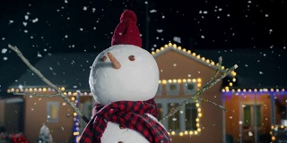 圣诞节前夕，戴着帽子和围巾的雪人站在装饰着花环的田园诗般的房子的后院。雪花在那个神奇的冬夜飘落。