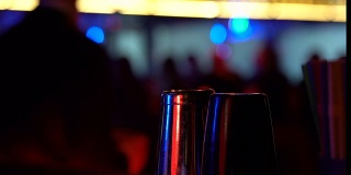 吧台上的摇酒器在跳舞的男人的背景下，夜生活的享受，酒精