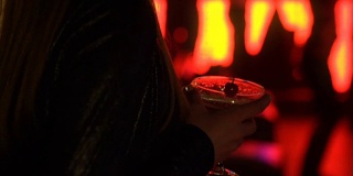 年轻的女士拿着鸡尾酒杯跳舞，享受夜店音乐，周末放松