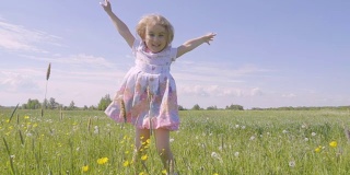 可爱的小女孩在蒲公英的颜色的草地上跳跃。孩子们在户外欢声笑语。夏天阳光灿烂的日子。缓慢的运动。