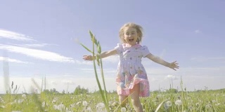 可爱的小女孩在蒲公英色的草地上奔跑。孩子们在户外欢声笑语。夏天阳光灿烂的日子。缓慢的运动。