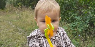 秋天的一天，小男孩手里拿着一个玩具在公园外面玩。
