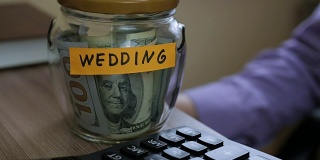 一个白人男人把一个玻璃罐子放在抽屉里，里面装着他的积蓄，为将来的婚礼做准备。