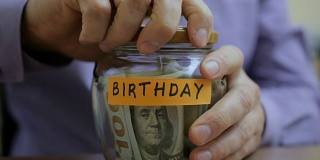 一个白人男子把一个玻璃罐放在抽屉里，里面装着他的积蓄，以备将来的生日之用
