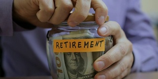 一个白种男人把一个玻璃罐放在抽屉里和他未来退休的积蓄放在一起