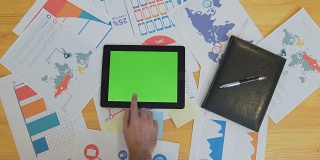 男人用绿色屏幕的平板电脑在办公桌上，工作空间，信息查找