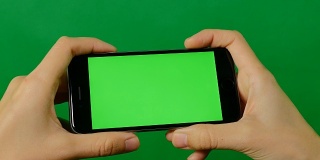 女商人用绿色背景的空白绿色屏幕手机。