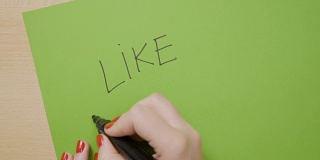 女性的手用黑色记号笔在绿色的纸上画了下划线
