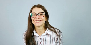 笑快乐聪明的女学生戴着光学眼镜在工作室在灰色背景摆姿势。