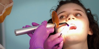 牙科医生用紫外光灯对十几岁的女性进行陶瓷填充
