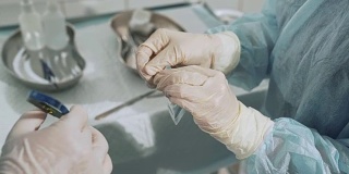 带无菌医疗器械的手术台。助手把手术刀刀片递给外科医生。医生的手与外科用品的特写镜头。健康理念，医院团队合作