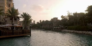 景观与运河，热带棕榈树和传统阿拉伯建筑与咖啡馆在晚上