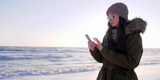 沉迷于网络，戴着眼镜的女人在海边玩智能手机