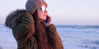 在海边度假时，女性戴着墨镜在户外打电话