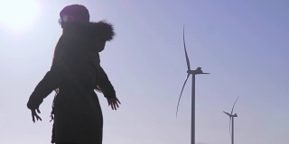 在阳光下旋转的风力发电站附近，一个黑色的女性身影