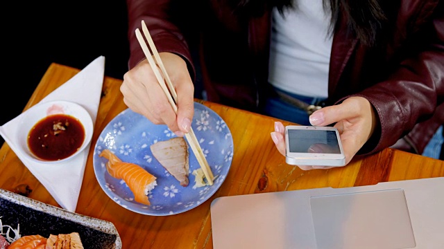 一个女人在4k餐厅边吃寿司边玩手机