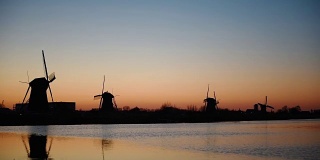 传统的荷兰风车在日落时从鹿特丹海峡。水镜的效果。荷兰
