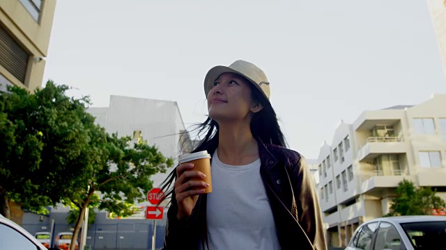 在城市街道喝咖啡的女人